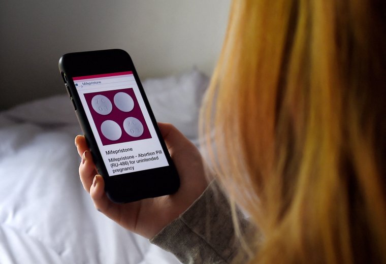 (FILES) In this file photo illustration taken on May 8, 2020, a woman looks at website with the Mifepristone Abortion Pill on her smart phone in Arlington, Virginia. - A conservative federal judge in the state of Texas halted US approval of the abortion pill mifepristone on Friday, but paused implementation for a week to give federal authorities time to appeal. (Photo by Olivier DOULIERY / AFP) (Photo by OLIVIER DOULIERY/AFP via Getty Images)