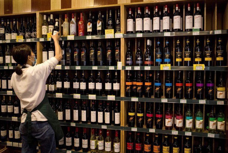 (FILES) This file photo taken on August 18, 2020 shows an employee placing a bottle of wine next to Australian made wine (R) at a store in Beijing. - China on December 10, 2020 said it had imposed fresh import duties on Australian wine as it accused Canberra of giving firms subsidies, in the latest salvo in a bitter stand-off following last month's swingeing anti-dumping tariffs. (Photo by Noel CELIS / AFP) / China OUT (Photo by NOEL CELIS/AFP via Getty Images)