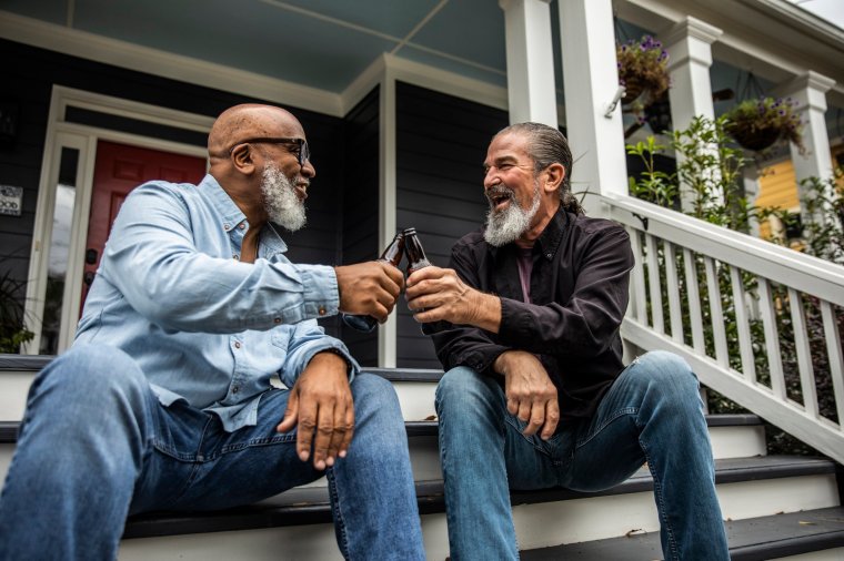 Senior men having beers and talking on front porch