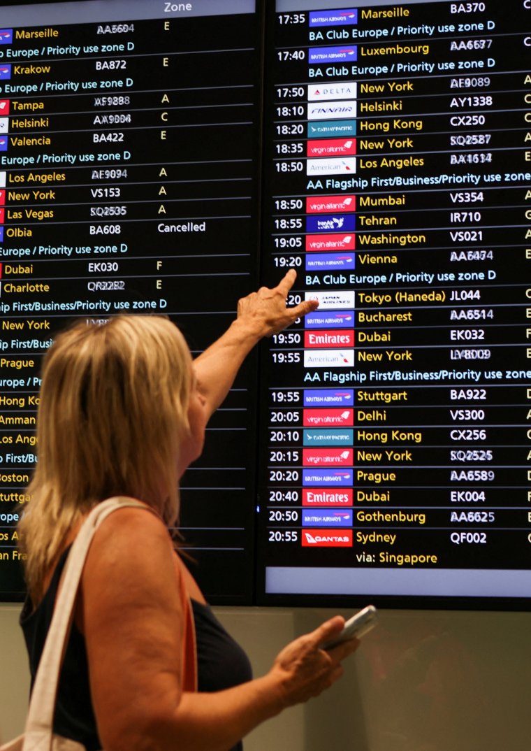 A woman points at a flight board at Heathrow Airport, as Britain's National Air Traffic Service (NATS) restricts UK air traffic due to a technical issue causing delays, in London, Britain, August 28, 2023. REUTERS/Hollie Adams