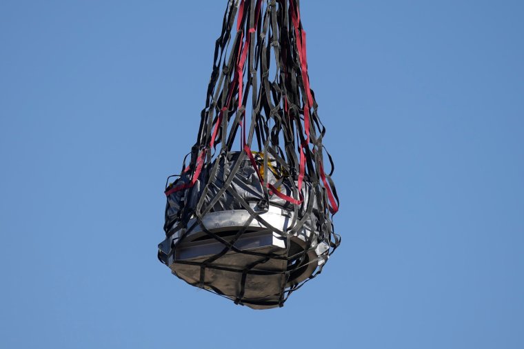 A helicopter delivers a space capsule carrying NASA's first asteroid samples on Sunday, Sept. 24, 2023, to a temporary clean room at Dugway Proving Ground, in Utah. The Osiris-Rex spacecraft released the capsule following a seven-year journey to asteroid Bennu and back. (AP Photo/Rick Bowmer, Pool)