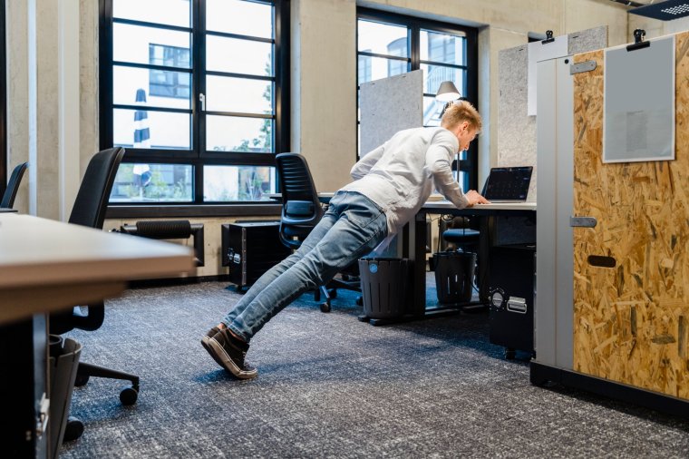 Young businessman doing push-ups at workplace