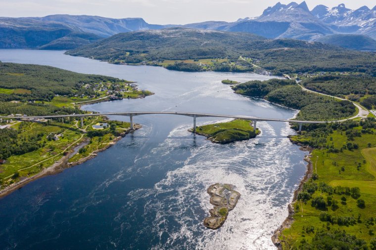 Scenic view of the Saltstraumen bridge crossing the Saltstraumen strait on a sunny day in Saltstraumen, Norway. This box girder bridge was opened in 1978 and is made of prestressed concrete making it strong against tensile forces. The Saltstraumen strait has one of the strongest tidal wave in the world thus, whirlpools can also be seen under the bridge.