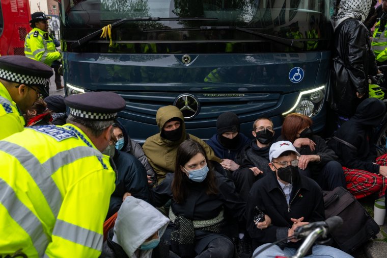 LONDON, ENGLAND - MAY 2: Police officers prepare to move protesters surrounding a bus that was to be used to carry migrants from a hotel on May 2, 2024 in Peckham, London, England. Protest groups including the Antiraids Network have vowed to stop migrant removals by the Home Office from hotels and premises across the UK. The Government passed the controversial Rwanda Bill last week and has set about detaining migrants ahead of deportation to Rwanda. (Photo by Carl Court/Getty Images)