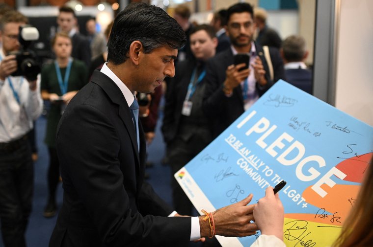 Britain's Chancellor of the Exchequer Rishi Sunak signs his name on a pledge to be an ally to the LGBT+ community at their stand on the second day of the annual Conservative Party Conference being held at the Manchester Central convention centre in Manchester, northwest England, on October 4, 2021. (Photo by Oli SCARFF / AFP) (Photo by OLI SCARFF/AFP via Getty Images)