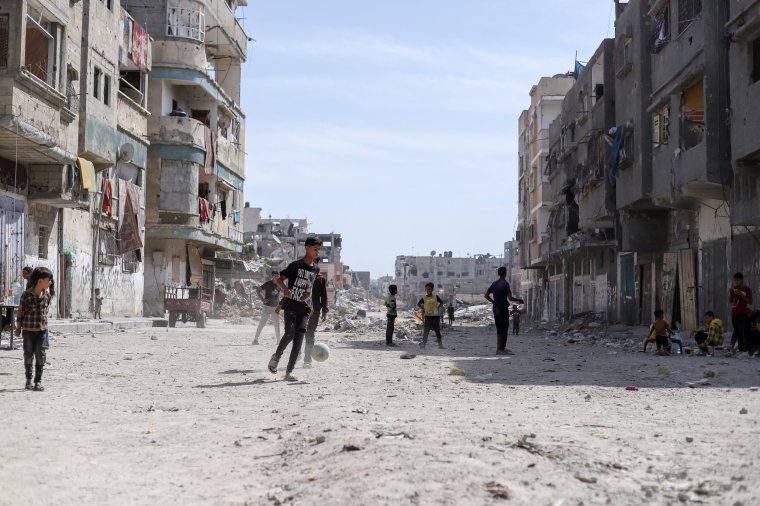 Palestinian children play football next ot the rubble in Khan Yunis after the Israeli army withdrew from the area on May 02, 2024. Israel's war on the Gaza Strip has turned most of the highly populated area into rubble, with thousands displaced from their homes to displacement camps. Despite the scale of destruction, several Palestinian families have returned to their homes covered with debris from the Israeli operation in the town. Israel has announced an operation on the city of Rafah, which is most likely to exacerbate the already dire situation of the Palestinians and displace more people from their home. (Photo by Khames Alrefi / Middle East Images / Middle East Images via AFP) (Photo by KHAMES ALREFI/Middle East Images/AFP via Getty Images)