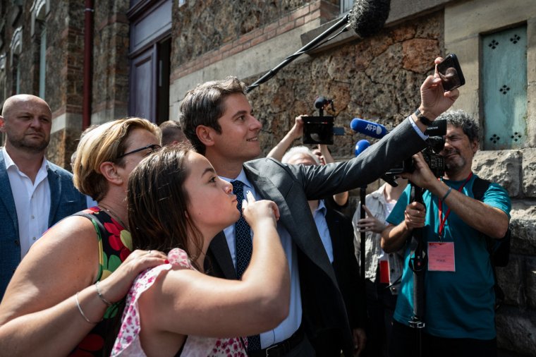 France's Prime Minister Gabriel Attal (C) takes a selfie with two women in front of a polling station after voting for the first round of parliamentary elections in Vanves, suburb of Paris on June 30, 2024. A divided France is voting in high-stakes parliamentary elections that could see the anti-immigrant and eurosceptic party of Marine Le Pen sweep to power in a historic first. The candidates formally ended their frantic campaigns at midnight June 28, with political activity banned until the first round of voting. (Photo by ARNAUD FINISTRE / POOL / AFP) (Photo by ARNAUD FINISTRE/POOL/AFP via Getty Images)