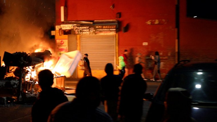 A man throws an item onto a fire during unrest in Harehills, Leeds, Britain, July 18, 2024 in this still image obtained from social media video. ?@robin_singh? via Instagram/via REUTERS THIS IMAGE HAS BEEN SUPPLIED BY A THIRD PARTY. MANDATORY CREDIT.