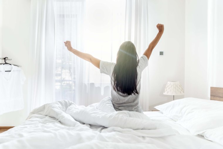 Freshly woken up young woman enjoying the morning sun rays.