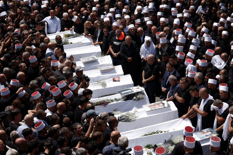 Druze elders and mourners surround the coffins of 10 of the 12 people killed in a rocket strike from Lebanon a day earlier, during a mass funeral in the Druze town of Majdal Shams in the Israel-annexed Golan Heights, on July 28, 2024. The Israeli military said the victims were struck by an Iranian-made rocket carrying a 50-kilogram warhead that was fired by Lebanese Hezbollah group at a soccer field in the Druze Arab town. Hezbollah has denied responsibility for the strike. (Photo by Jalaa MAREY / AFP) (Photo by JALAA MAREY/AFP via Getty Images)