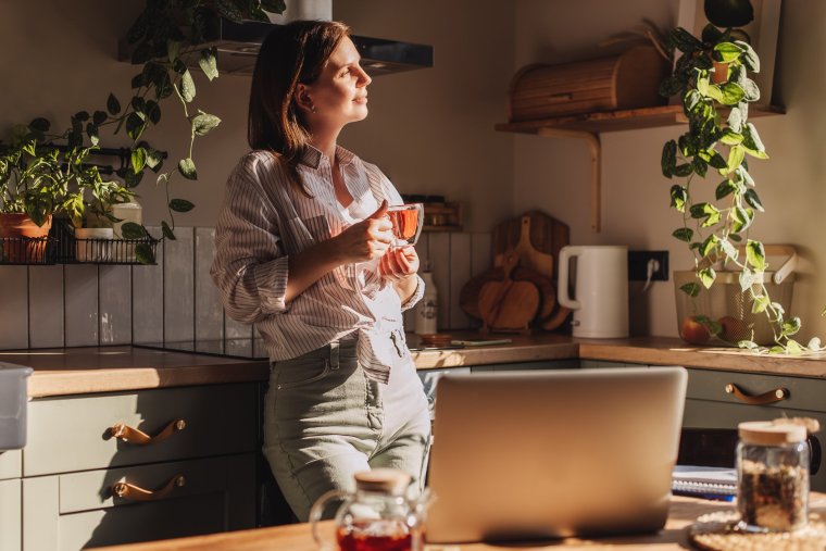 Young happy woman drinking coffee on the kitchen in the morning.