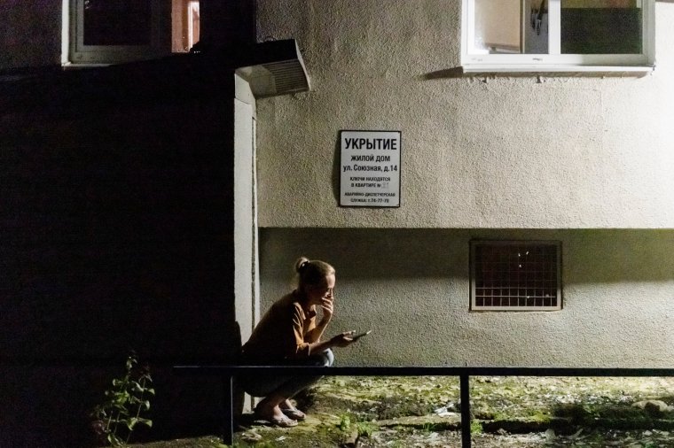 A resident of the apartment building damaged after shelling by the Ukrainian side holds her smart phone sitting at the door of the shelter in Kursk, Russia, Sunday, Aug. 11, 2024. (AP Photo)