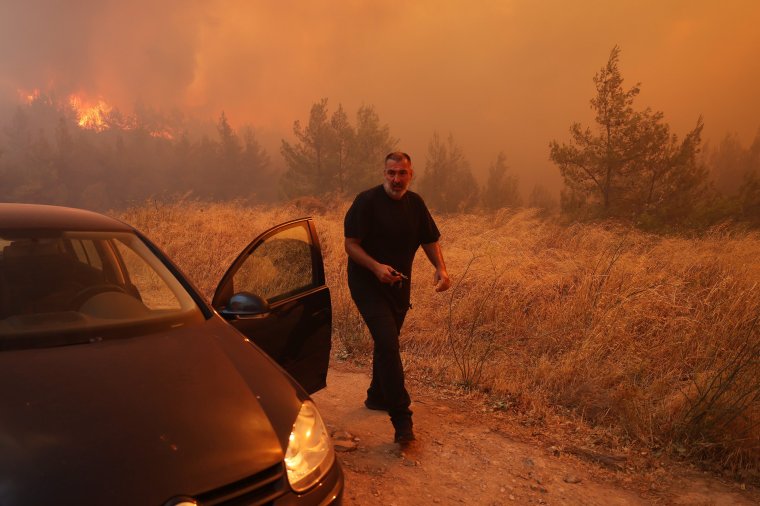 ATHENS, GREECE - AUGUST 12: A man evacuates his house during a wildfire in Dione near Athens, Greece, on August 12, 2024. A major fire that broke out Sunday in the northeastern town of Varnavas in Greece's Attica region continues to rage, forcing residents of nearly 10 villages to evacuate in the very early hours of Monday after many homes were damaged, local media reported. (Photo by Costas Baltas/Anadolu via Getty Images)