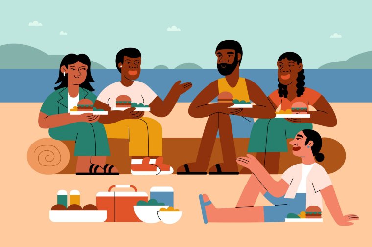 A multiracial group of queer LGBTQIA friends enjoy a picnic together on the beach lakefront in the summer