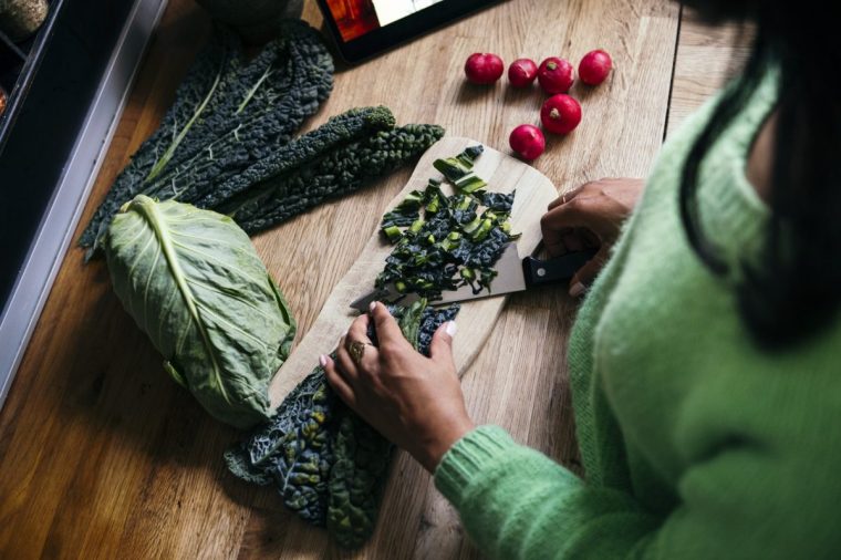 Woman cutting bitter gourd in kitchen