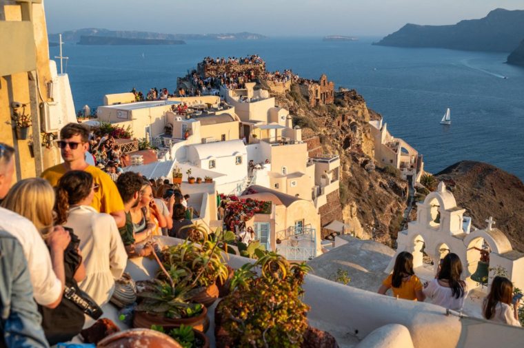 Travellers enjoying every bit of free space to admire the sunset at Oia on the island of Santorini, 30 June 2024. With the uncontested growth in the number of visitors to the island of Santorini, the authorities are beginning to think about imposing certain limits on the number of travellers. (Photo by Xavier Duvot / Hans Lucas / Hans Lucas via AFP) (Photo by XAVIER DUVOT/Hans Lucas/AFP via Getty Images)