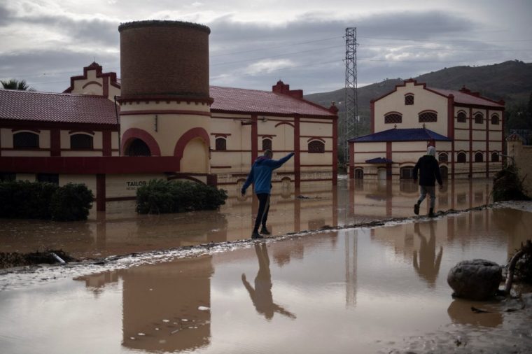 Men walk in a flooded street in Alora, near Malaga, on October 29, 2024, after heavy rains hit southern Spain. (Photo by JORGE GUERRERO / AFP) (Photo by JORGE GUERRERO/AFP via Getty Images)