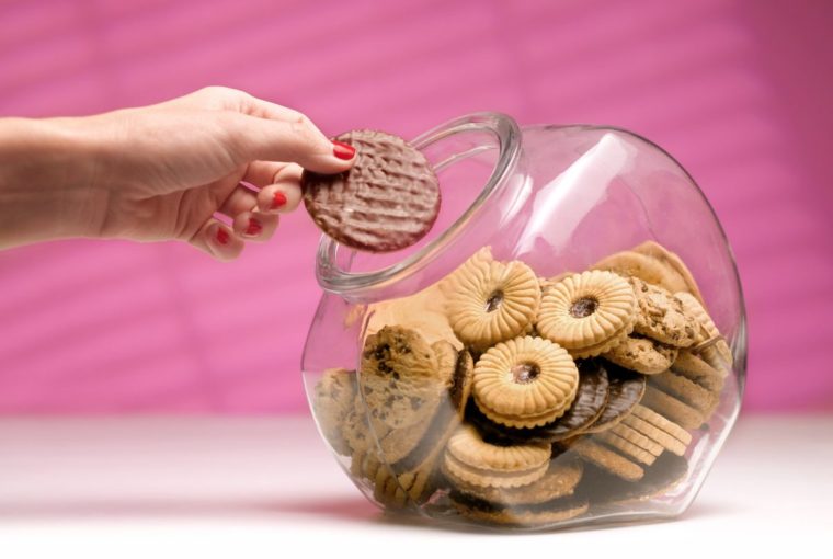 dieting woman sneaking a biscuit treat from the cookie jar