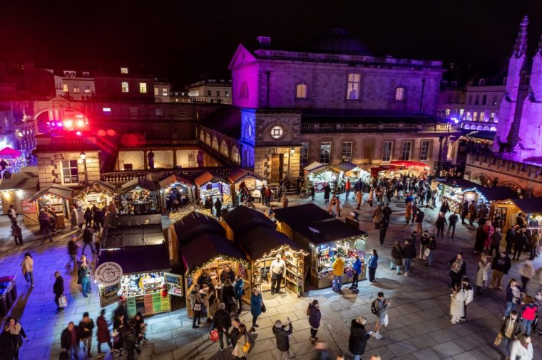 BATH, ENGLAND - DECEMBER 12: Christmas shoppers browse stalls in the Abbey Courtyard at the traditional Christmas market that has opened in the centre of the historic city on December 12, 2023 in Bath, England. Originating in Germany, Christmas markets have become increasingly popular in many British towns and cities in recent years as a way of boosting festive sales and visitor numbers. (Photo by Matt Cardy/Getty Images)