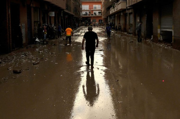 MASSANASSA, SPAIN - NOVEMBER 07: A man walks through mud in the street as the area recovers from last week's widespread flooding on November 07, 2024 in the municipality of Massanassa near Valencia, Spain. A week after the floods, Spanish authorities confirmed that at least 214 people had died, mostly in the Valencia region, amid the flooding that swept eastern and southern parts of the country starting on Tuesday. The intense rainfall event is known as a "cold drop" or DANA weather system. (Photo by David Ramos/Getty Images)