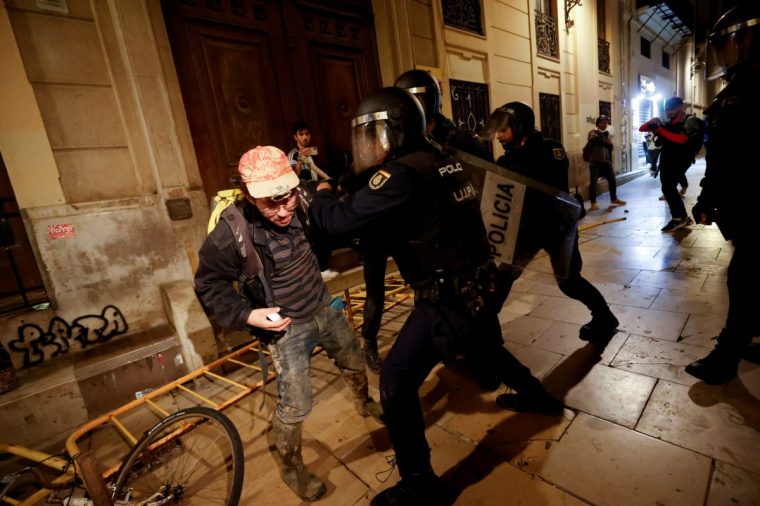 Police officers in riot gear restrain a man during a protest against Valencia's regional leader Carlos Mazon and the management of the emergency response to the deadly floods in eastern Spain, in Valencia, Spain, November 9, 2024. REUTERS/Eva Manez