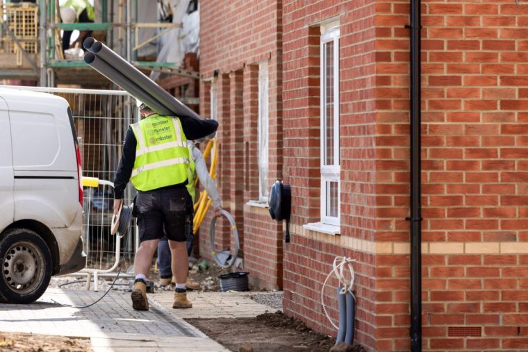 A construction worker carries piping in to a house under construction at a Barratt Developments Plc housing estate in Boroughbridge, UK, on Tuesday, Sept. 10, 2024. The government laid out proposals to boost development this summer, promising to restore mandatory local housebuilding targets that were ditched by the previous Conservative administration. Photographer: Chris Ratcliffe/Bloomberg via Getty Images