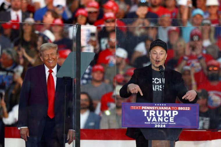 FILE PHOTO: Tesla CEO and X owner Elon Musk speaks as Republican presidential nominee and former U.S. president Donald Trump reacts during a rally at the site of the July assassination attempt against Trump, in Butler, Pennsylvania, U.S., October 5, 2024. REUTERS/Carlos Barria/File Photo/File Photo