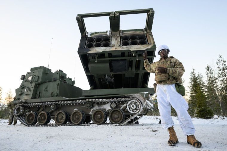 ROVANIEMI, FINLAND - NOVEMBER 20: Major Ronnie Drammeh of the US Army 1st Battalion, 6th Field Artillery Regiment speaks to members of the media as he stands with a MLRS M270 A2 mobile rocket system during the NATO "Exercise Lightning Strike" on November 20, 2024 near Heinu, Finland. The live-fire exercise includes service members from 28 Allied and partner nations, and is taking place between November 4-24, across locations in Finland, Estonia, Germany, Poland, and Romania. (Photo by Leon Neal/Getty Images)