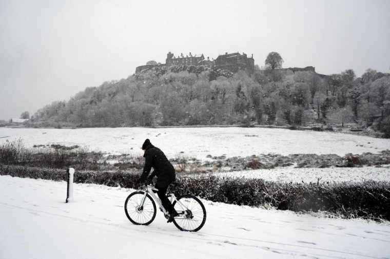 A person rides a bicycle in the snow at Stirling Castle, Stirling, Scotland. Storm Bert is battering the country with strong winds, heavy rain and snow and ice with amber warnings coming into force bringing a "potential risk to life and property". Picture date: Saturday November 23, 2024. PA Photo. See PA story WEATHER Bert . Photo credit should read: Andrew Milligan/PA Wire