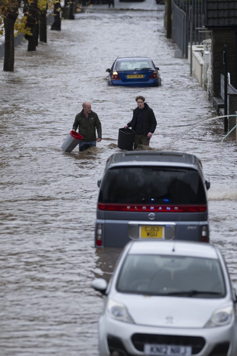 PONTYPRIDD, WALES - NOVEMBER 24: People wade through water on Sion Street on November 24, 2024 in Pontypridd, Wales. The UK Met Office issued warnings for heavy rain and snow, along with strong winds, as Storm Bert was forecast to sweep across the UK this weekend. (Photo by Matthew Horwood/Getty Images)