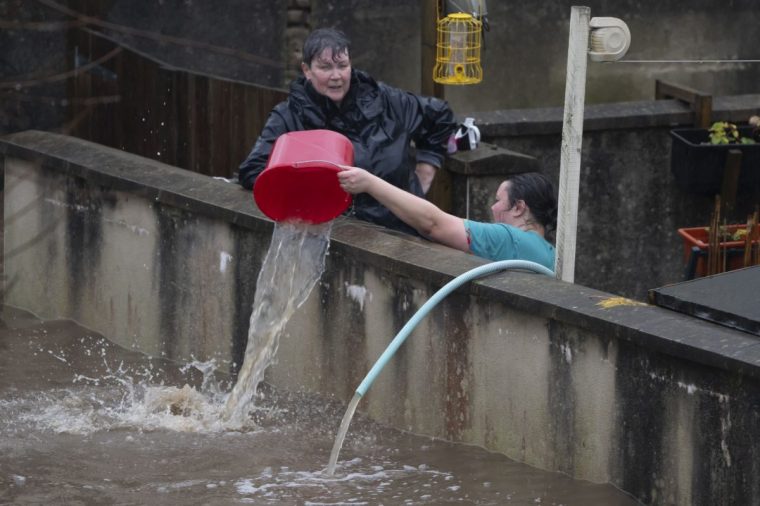 PONTYPRIDD, WALES - NOVEMBER 24: People pour water out of the front garden of properties on Sion Street on November 24, 2024 in Pontypridd, Wales. The UK Met Office issued warnings for heavy rain and snow, along with strong winds, as Storm Bert was forecast to sweep across the UK this weekend. (Photo by Matthew Horwood/Getty Images)