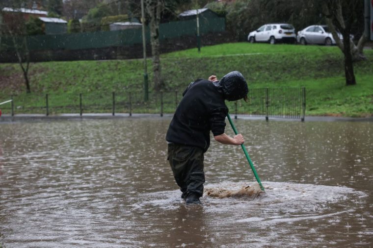 ABERCARN, NEWPORT, WALES - NOVEMBER 24: Residents of Abercarn attempt to clear drains to allow the water to subside on November 24, 2024 in Abercarn, Newport, Wales. The UK Met Office issued warnings for heavy rain and snow, along with strong winds, as Storm Bert was forecast to sweep across the UK this weekend. (Photo by Huw Fairclough/Getty Images)