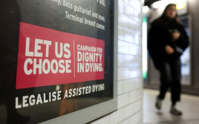 A tube passenger walks past an assisted-dying rights billboard ahead of the parliamentary debate on Friday, in London, Britain November 26, 2024. REUTERS/Mina Kim