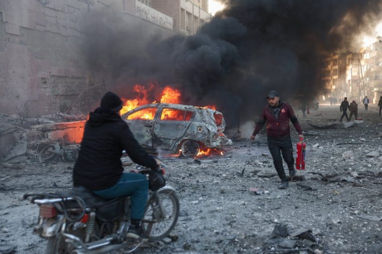 TOPSHOT - People try to extinguish fires following an airstrike that targeted Syria's rebel-held northern city of Idlib on December 2, 2024. (Photo by Omar HAJ KADOUR / AFP) (Photo by OMAR HAJ KADOUR/AFP via Getty Images)