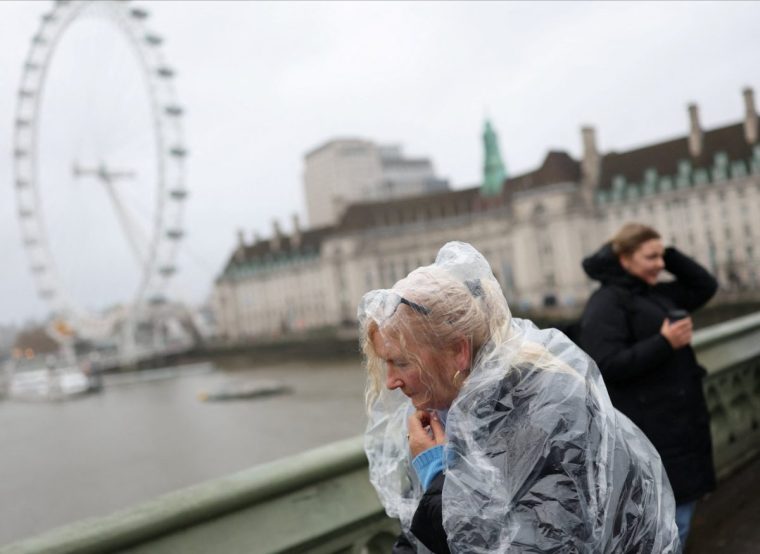 A tourist wearing a raincoat walks on Westminster Bridge during a gust of wind, after Storm Darragh hit the country, in London, Britain, December 7, 2024. REUTERS/Isabel Infantes