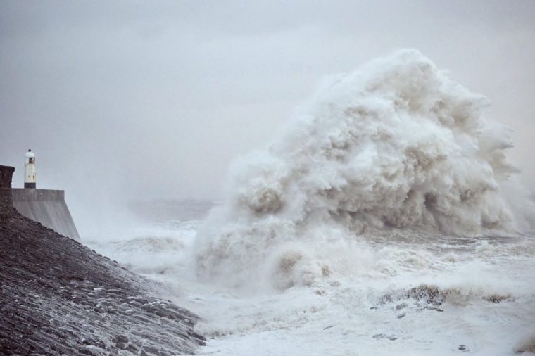 TOPSHOT - Waves crash against the sea wall and lighthouse at Porthcawl, south Wales, on December 7, 2024, as storm darragh brings winds of nearly 90 mph to the west of Wales and north-west England. High winds and heavy rain have battered western parts of the United Kingdom, causing widespread travel disruption. (Photo by Ben STANSALL / AFP) (Photo by BEN STANSALL/AFP via Getty Images)