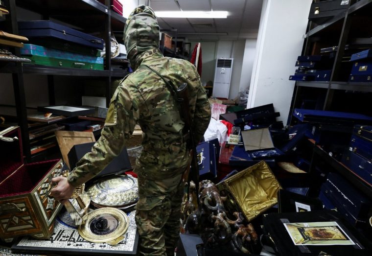 A rebel fighter holds and looks at personal souvenirs of Syria's Bashar al-Assad at one of the rooms in the Presidential Palace known as Qasr al-Shaab "People's Palace", after rebels seized the capital and ousted Syria's Bashar al-Assad, in Damascus, Syria December 10, 2024. REUTERS/Amr Abdallah Dalsh