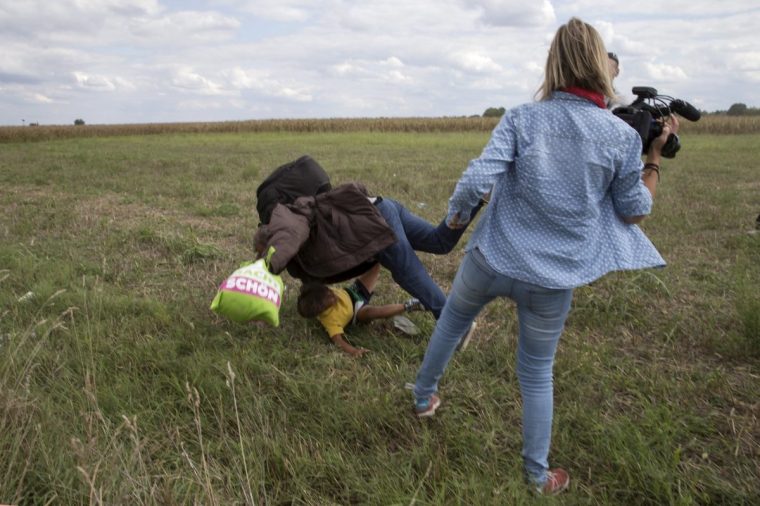 A Syrian refugee, Osama Abdul Mohsen, carrying his youngest son Zaid falls after being tripped by TV camerawoman Petra Laszlo (R) while trying to escape from a collection point in Roszke village, Hungary, September 8, 2015. Osama Abdul Mohsen's story went viral after he was filmed being tripped up by a camerawoman as he fled police near the Hungarian border with Serbia last September. He was carrying his youngest son Zaid in his arms at the time, and the two fell sprawling on the ground. Footage of the incident helped bring him to the attention of a soccer training school in Getafe on the outskirts of Madrid, which found him work as a liaison officer. REUTERS/Marko Djurica/File Photo SEARCH "REFUGEE PEREZ" FOR THIS STORY. SEARCH "THE WIDER IMAGE" FOR ALL STORIES