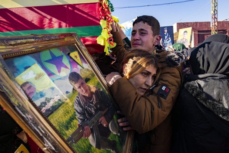 TOPSHOT - A relative holds a portrait of one of five fighters of the Kurdish-led Syrian Democratic Forces (SDF) who were killed in Manbij during clashes with Turkish-backed opposition factions earlier this week, during their funeral in Qamishli in northeastern Syria on December 14, 2024. Kurdish authorities have made overtures to Islamist-led rebels who seized power in Syria on December 8, but the long-oppressed community fears it could lose hard-won gains it made during the war, including limited self-rule. (Photo by Delil SOULEIMAN / AFP) (Photo by DELIL SOULEIMAN/AFP via Getty Images)