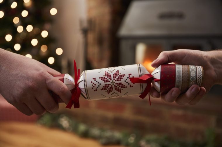 Couple Pulling Cracker In Room Decorated For Christmas