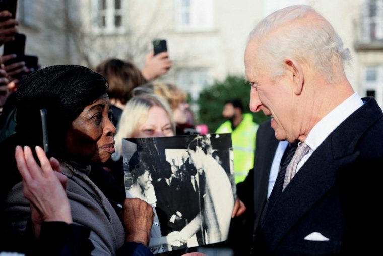 Britain's King Charles III speaks with Caroline Akuffo (L), who shows him a photograph of them meeting in Japan in 1970, during a reception at Waltham Forest Town Hall in London on December 20, 2024. (Photo by Mina Kim / POOL / AFP) (Photo by MINA KIM/POOL/AFP via Getty Images)