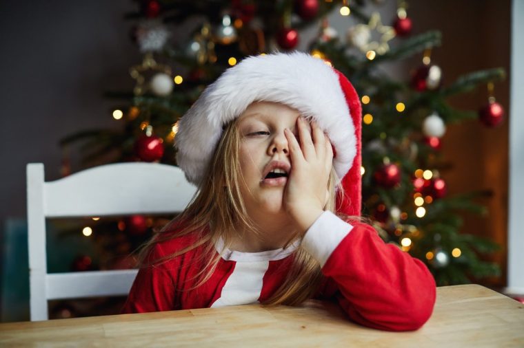 Portrait of a tired little girl with a Christmas hat on