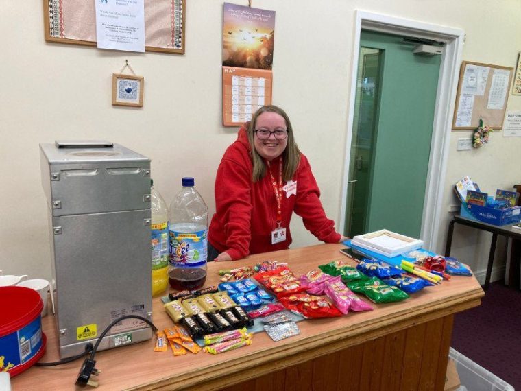 Carmela Falcone, 26, who has Down's syndrome, was given the chance to socialise in a safe space by The i Paper?s Christmas appeal charity Action for Children. She now volunteers to help other young people. Carmela running the tuck shop (Photo: Action for Children)