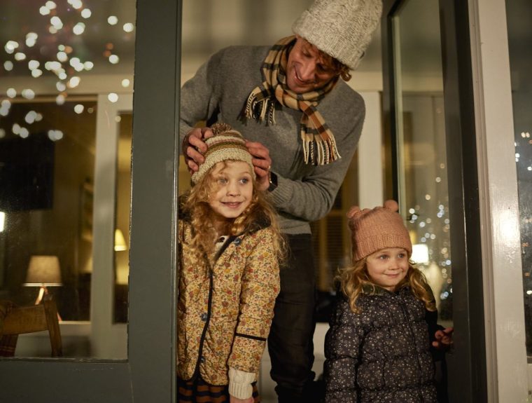 Young sisters warmed up warm, enjoying watching fireworks from their home with their dad