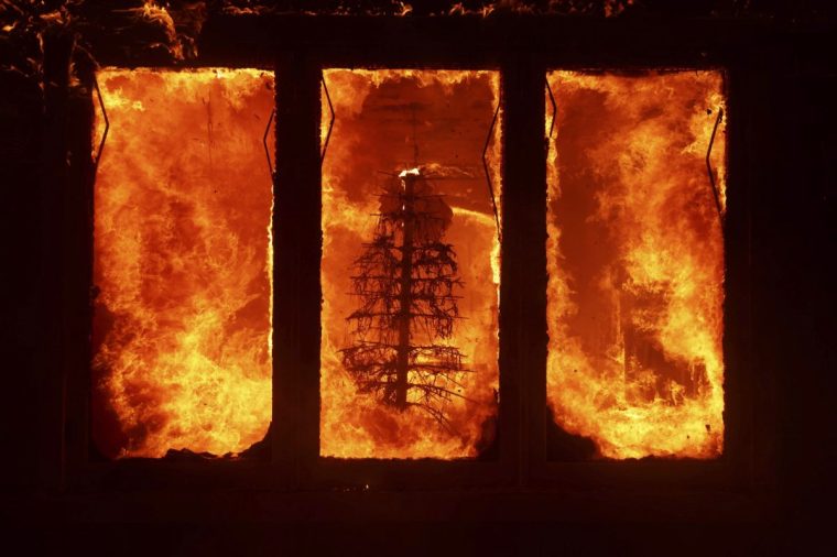 The Palisades Fire burns a Christmas tree inside a residence in the Pacific Palisades neighborhood of Los Angeles, Tuesday, Jan. 7, 2025. (AP Photo/Ethan Swope)