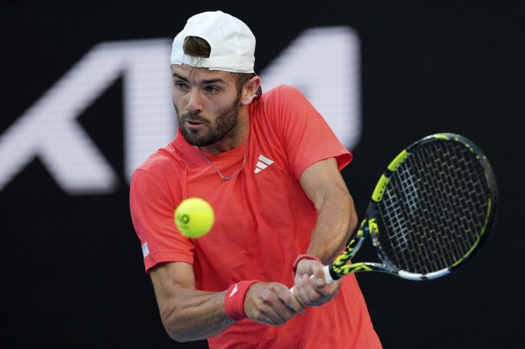 Jacob Fearnley of Britain plays a backhand return to Nick Kyrgios of Australia during their first round match at the Australian Open tennis championship in Melbourne, Australia, Monday, Jan. 13, 2025. (AP Photo/Ng Han Guan)