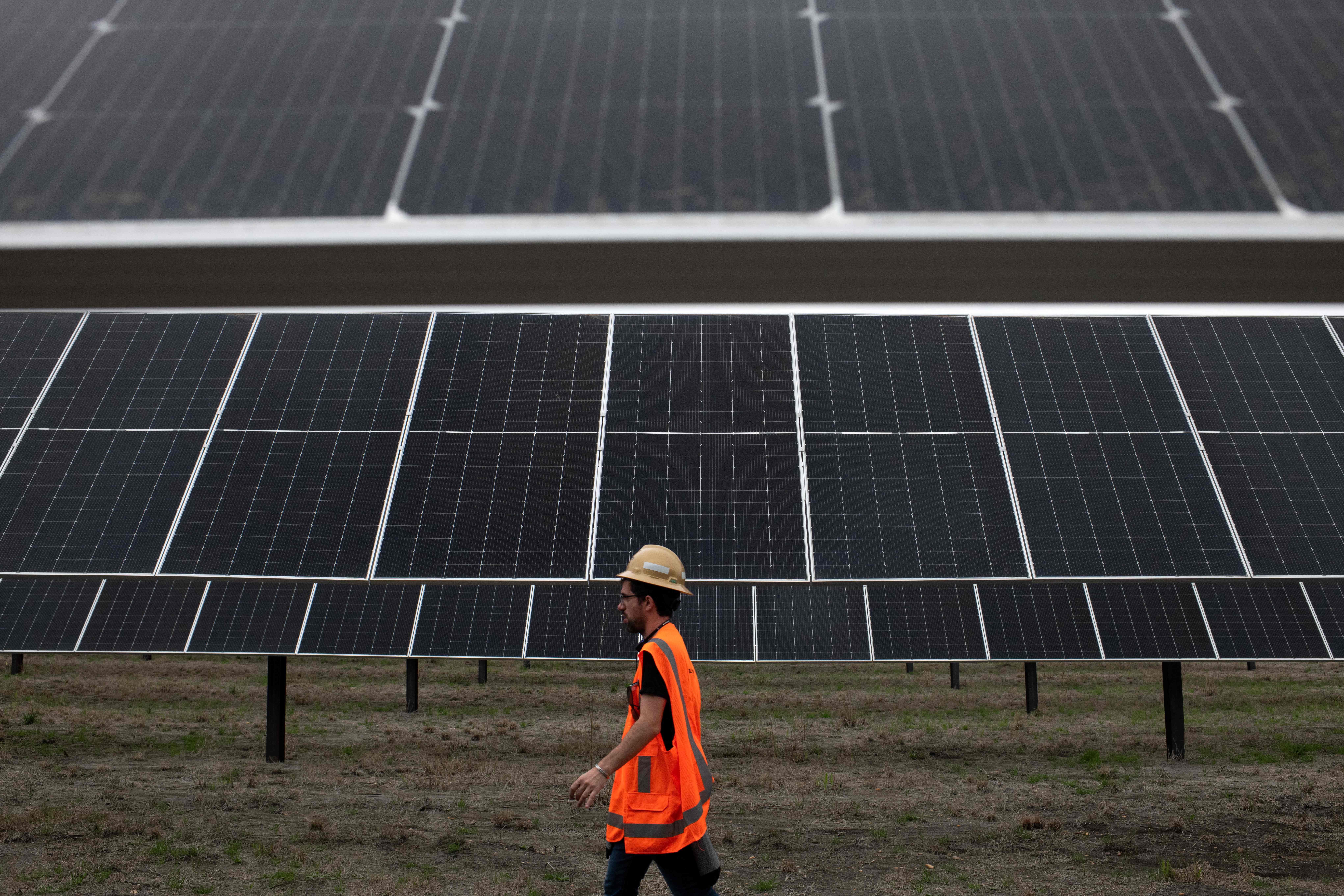 An ENGIE employee walks past solar panels at the ENGIE Sun Valley Solar project in Hill County, Texas, on March 1, 2023. Credit: Mark Felix/AFP via Getty Images