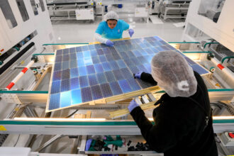 Workers place encapsulation material on solar panels at the Elin Energys solar panel manufacturing facility on April 25 in Brookshire, Texas. Credit: Brett Coomer/Houston Chronicle via Getty Images