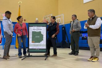 Secretary of the Interior Deb Haaland, second from the left, helped Pueblo of Jemez Gov. Peter Madalena, center, unveil a poster showing Valles Caldera National Preserve in north central New Mexico, during the event on December 22 celebrating the settlement upholding the pueblo’s entitlement to its ancestral land, including Banco Bonito, inside the national preserve. Credit: Noel Lyn Smith/Inside Climate News