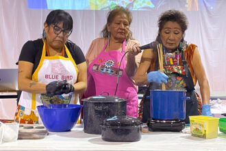 Tennile Lopez (left) shapes blue corn dough while Bertha Etsitty (right) explains the process of blue corn mush on Nov. 25 at the food gathering summit held by Diné College's Land Grant Office. Credit: Noel Lyn Smith/Inside Climate News